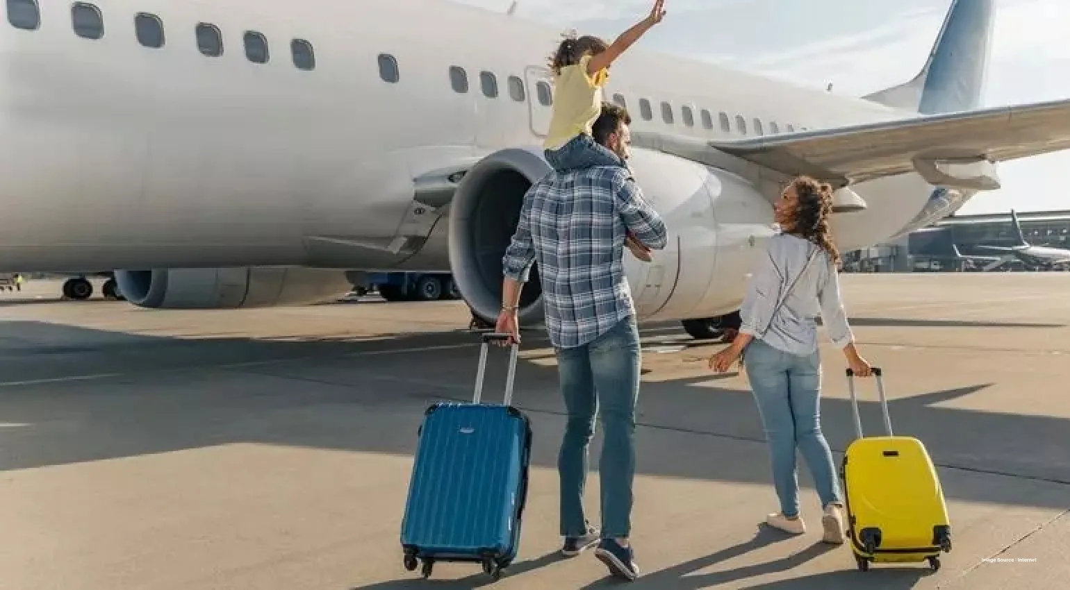 a family of three walking towards an airplace with suitcases