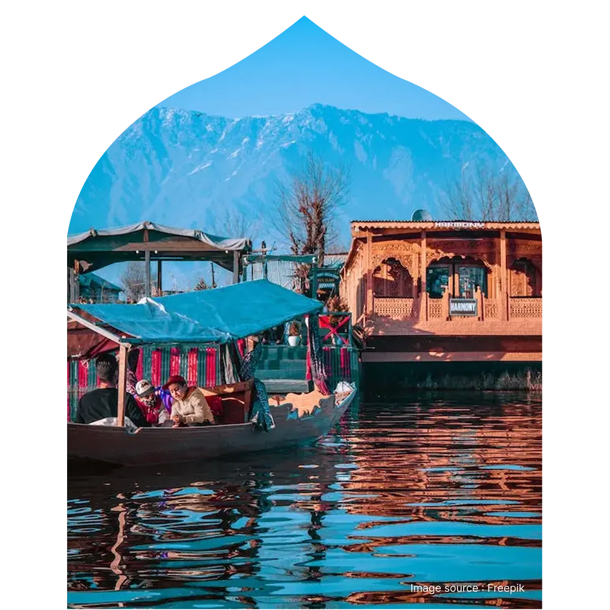 Tourists enjoying a Shikara boat ride on Dal Lake in Srinagar, Kashmir, with traditional wooden houseboats and snow-capped Himalayan mountains in the background.