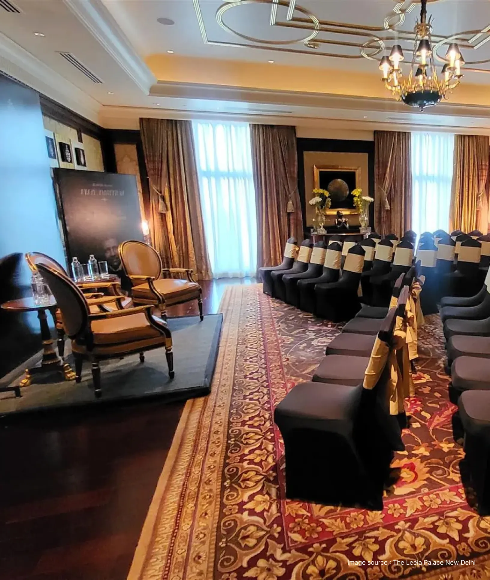 a meeting room at the Leela Palace with brown chairs and a stage