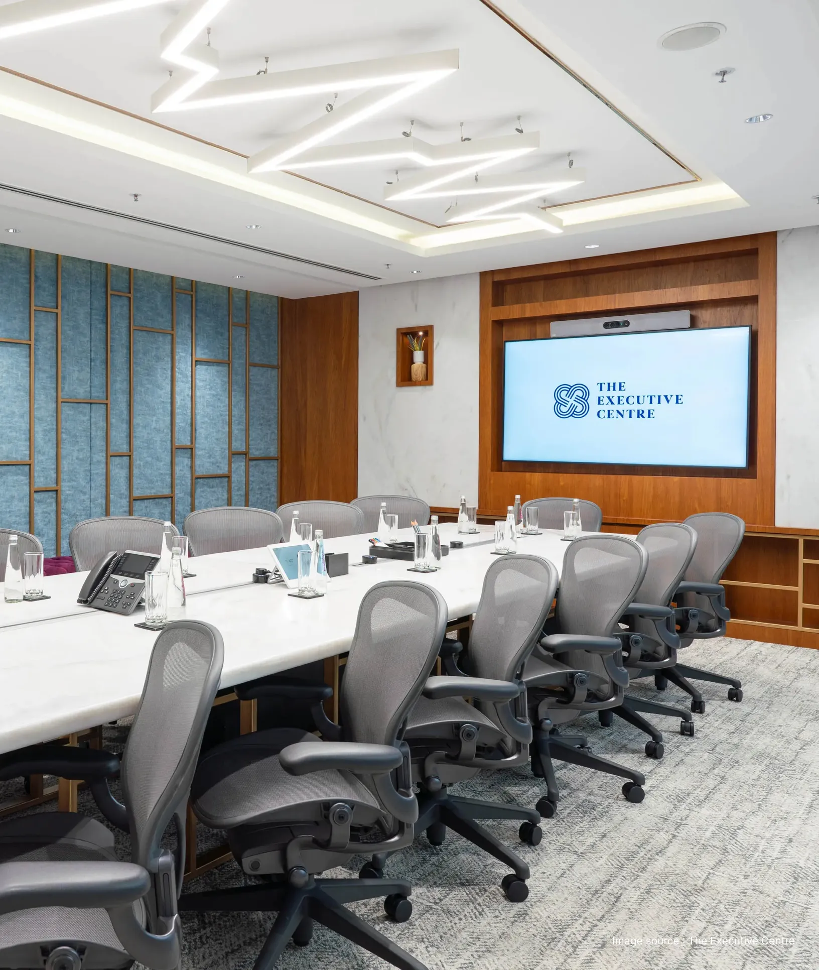 a meeting room with grey office chairs and a television