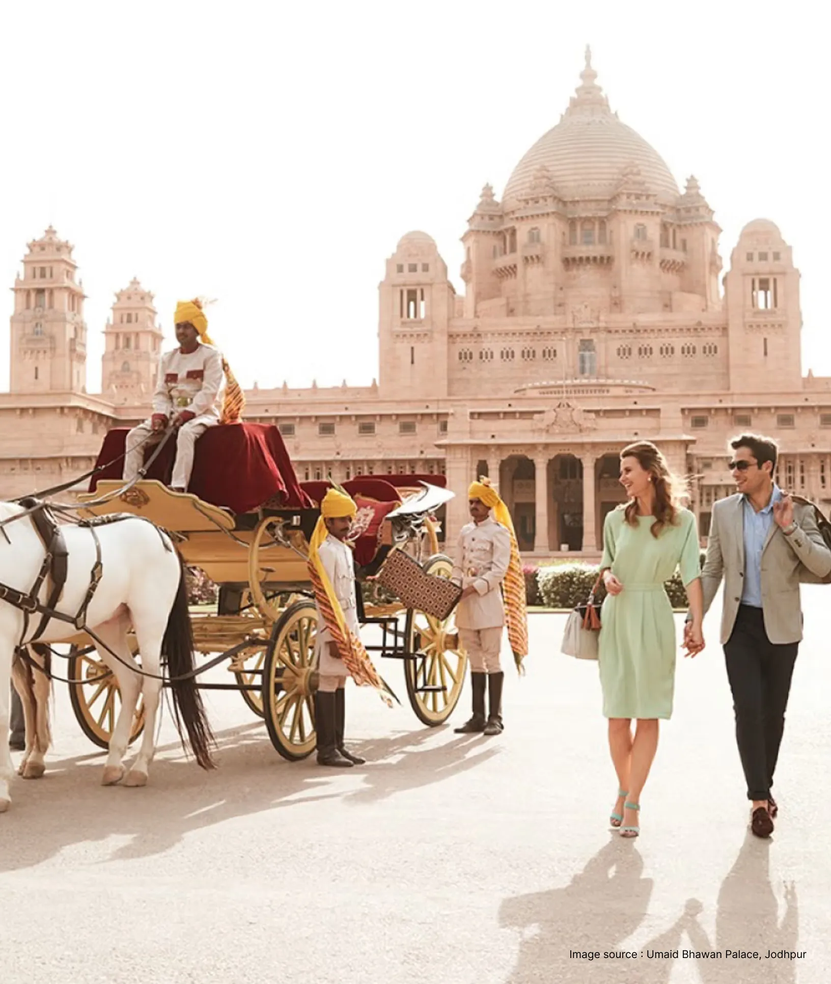 a horse carriage ride passes by a tourist couple at the umaid bhawan palace