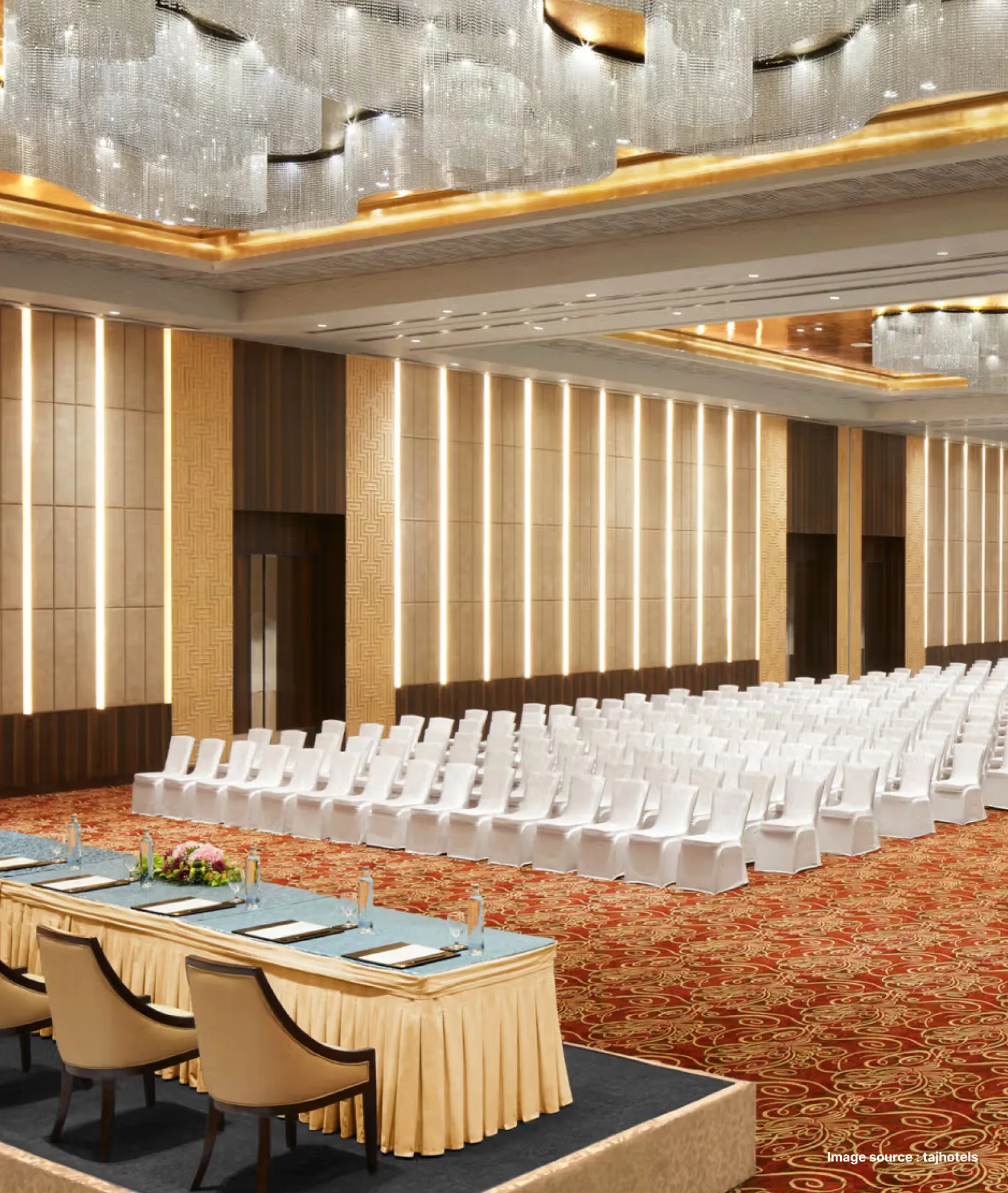 a conference hall in taj hotel with white chairs and a stage with setup