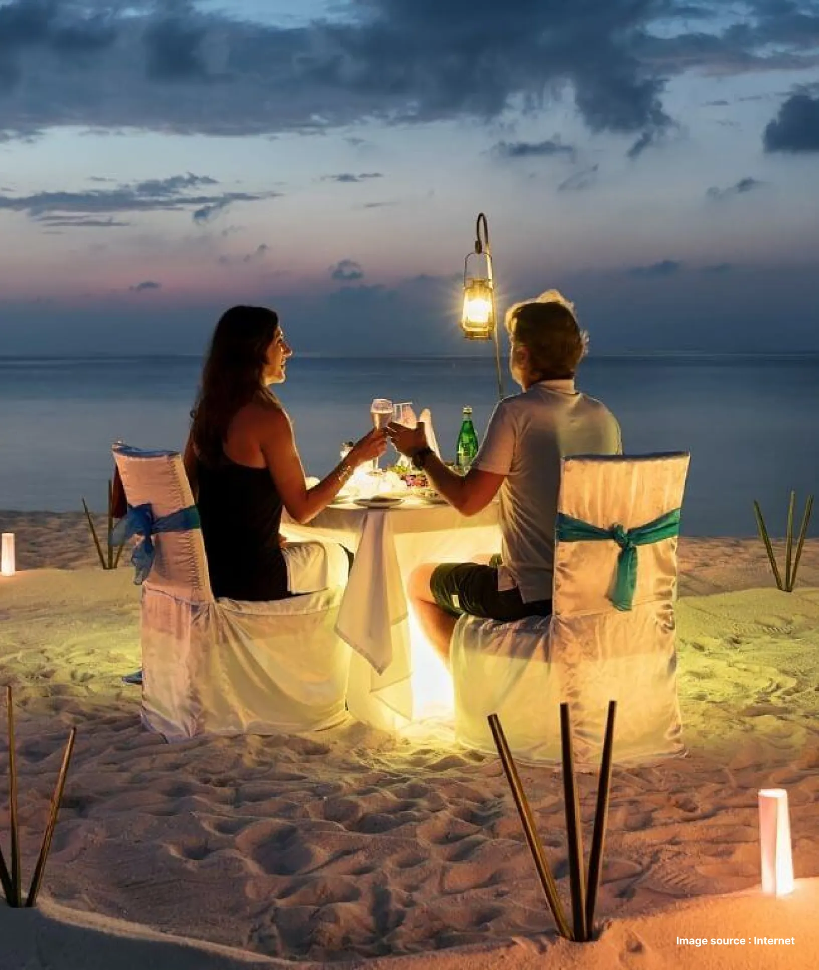 a couple enjoying dinner at a decorated pavilion at sunset