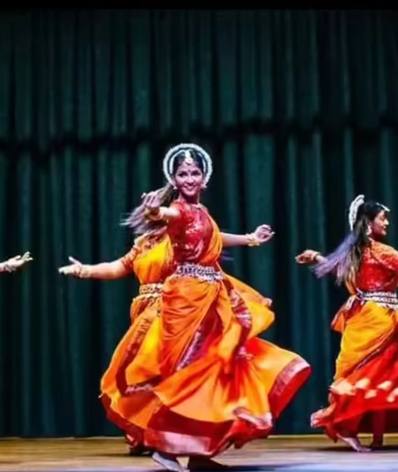 a group of young indian girls dressed in elaborate tradtionals performing odissi