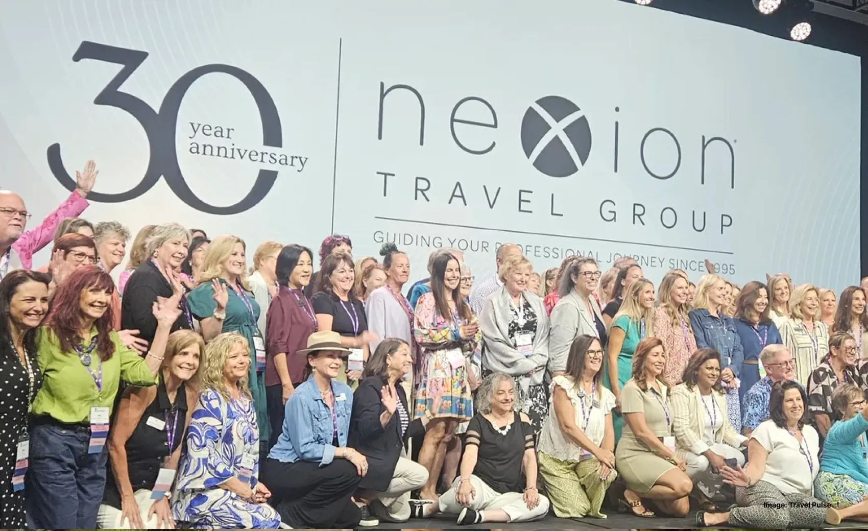 a group of nexion travel advisors on stage celebrating with "30 year anniversary" in the background 