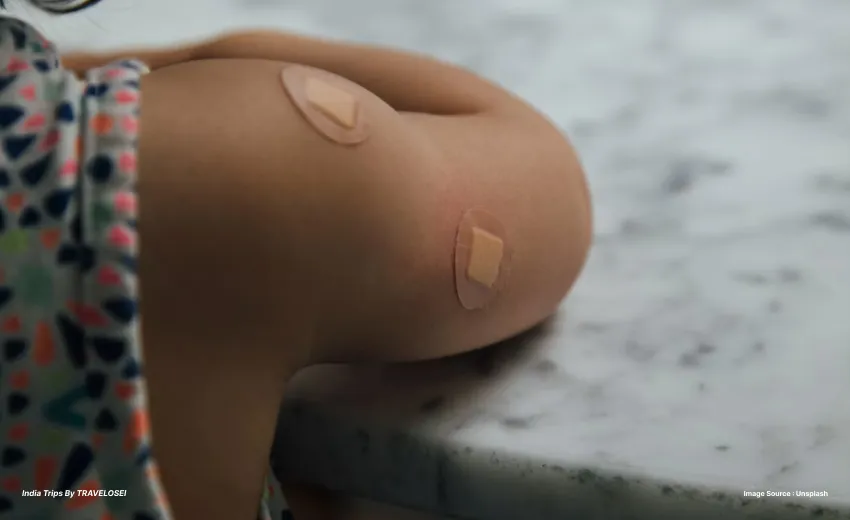a person’s arm post vaccination with two bandaids on them
