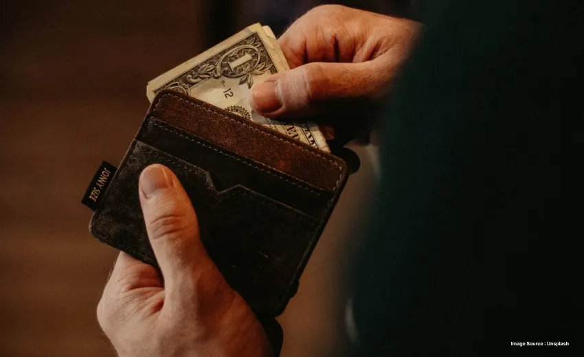 someone packing cash in a black wallet