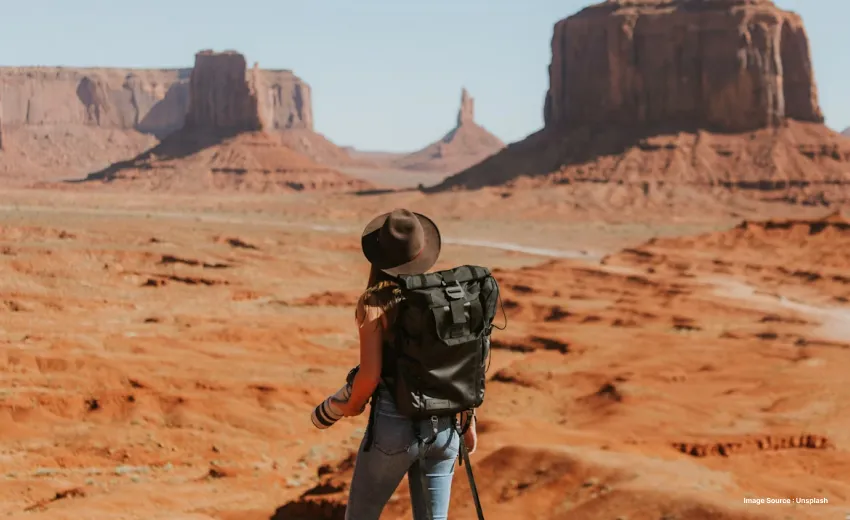 someone trecking on a desert looking towards the domes