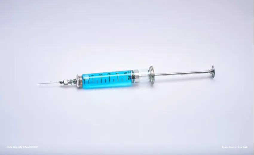 an image of a syringe against a white backdrop with blue liquid inside of it