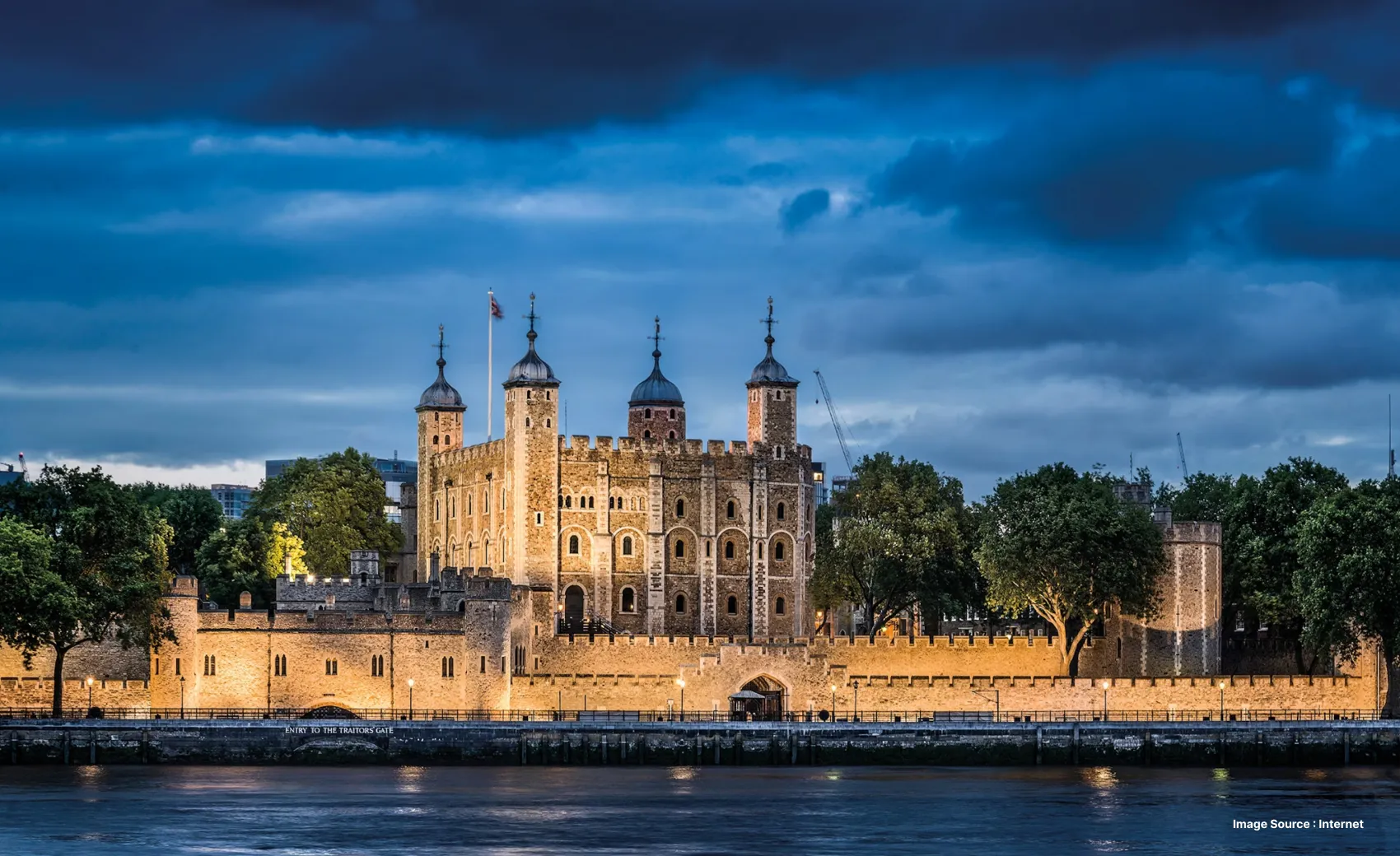 a nighttime view of the tower of london lit up in front of the river and dusky sky