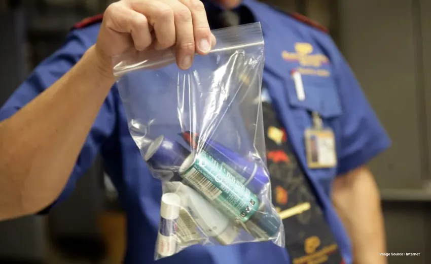 A uniformed staff holding up a Ziploc bag with confiscated liquids
