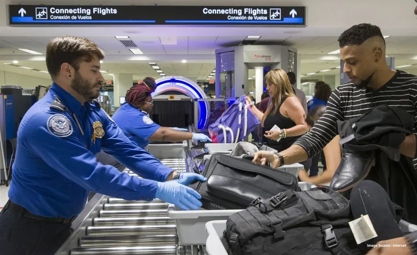 a uniformed security personnel checking luggage at the airport with gloves on