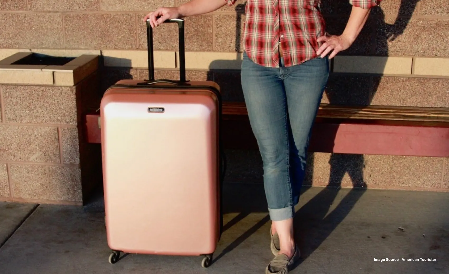 a woman poses with a pink hard shell suitcase