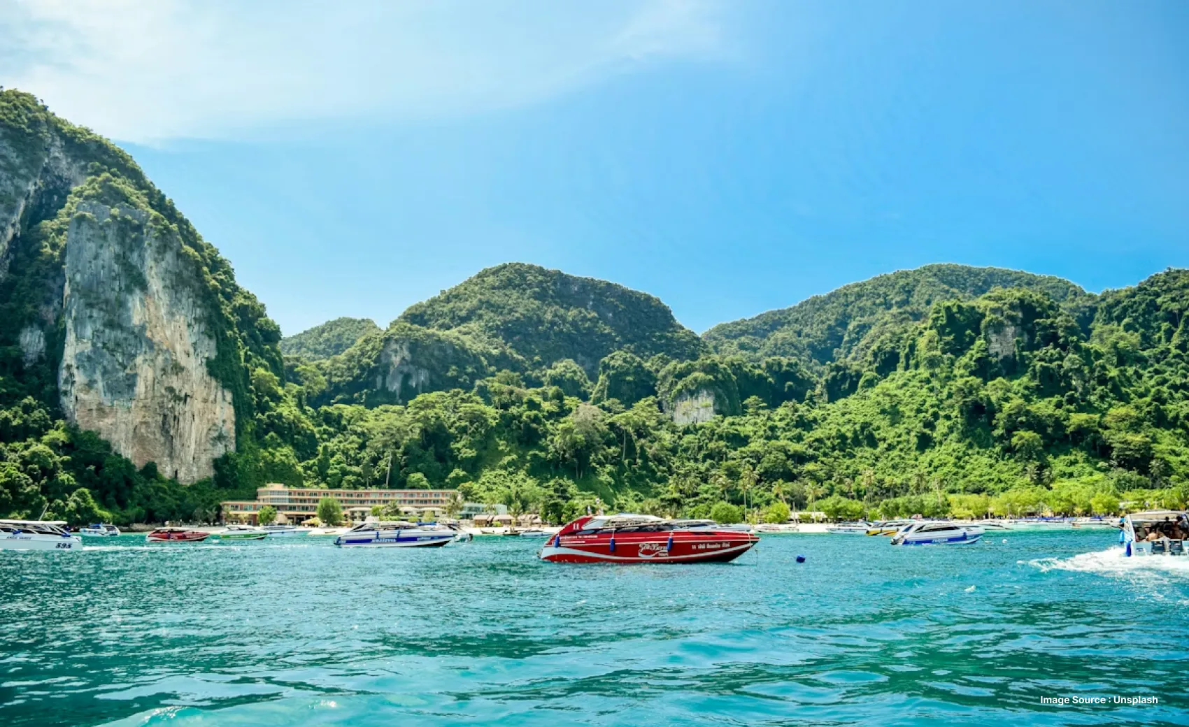 lush green peaks with turquoise Water in front and a red boat cruising