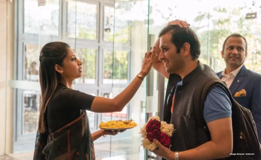 a hotel staff woman welcoming a foreigner guest with tilar ceremony and flowers 