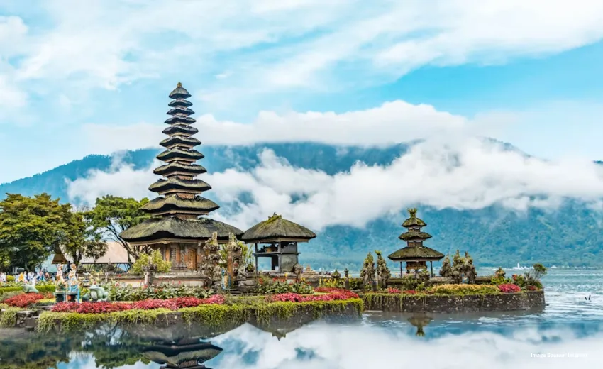 Traditional lakeside temple with mountains and clouds in the background.