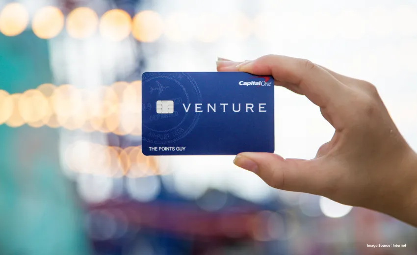 a person holding up the venture credit card with a blurry background