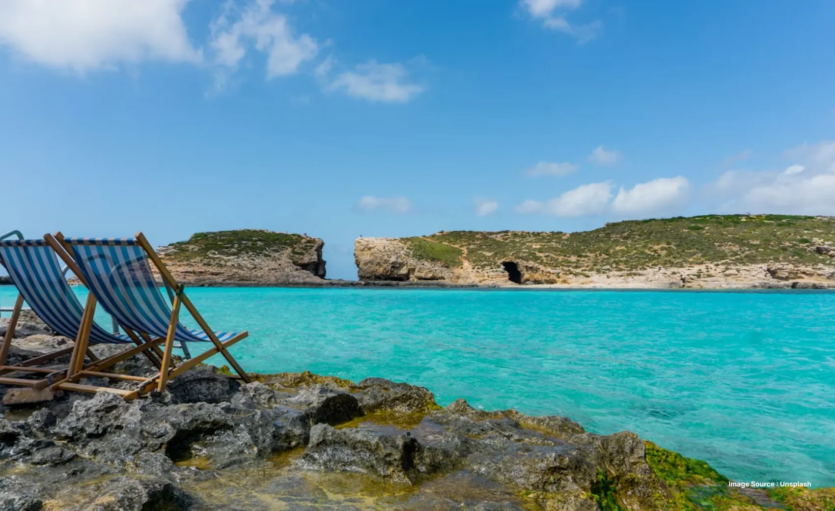 two lounge chairs with striped fabric on a rugged cliff overlooking the bluelagoon