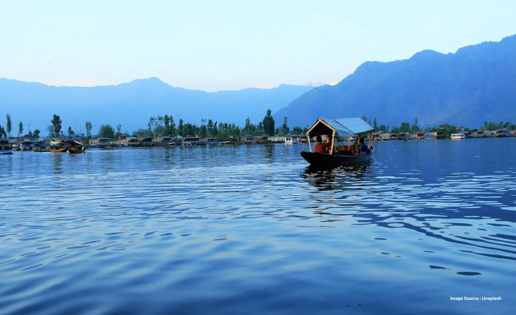 distant views of himalayan peaks from the dal lake in srinagar as tourists enjoy a shikara boat ride
