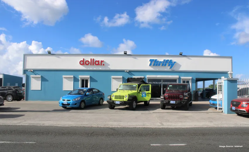 different colorful cars parked outside of dollar and thrifty car rental outlets on a sunny day