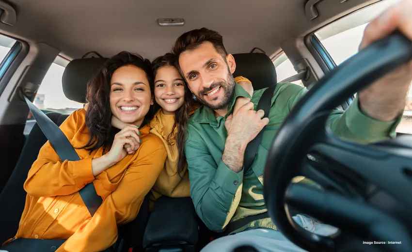 a family of three happily posing while inside the car with hands around each other