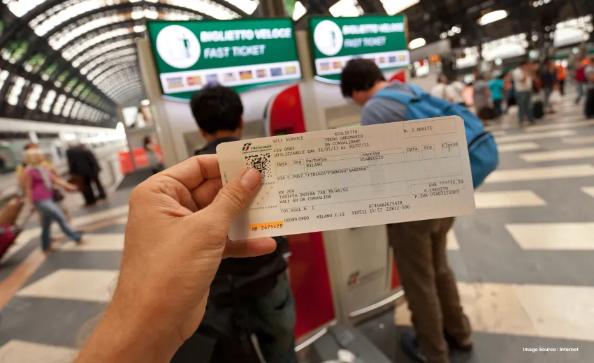 a person holding up a train pass at a busy railway station