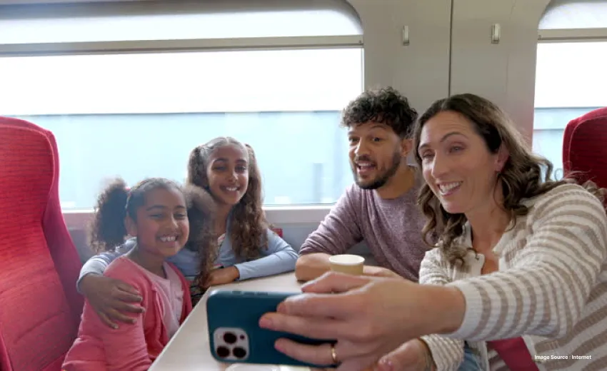 a family of 4 poses for a selfie sitting inside a train