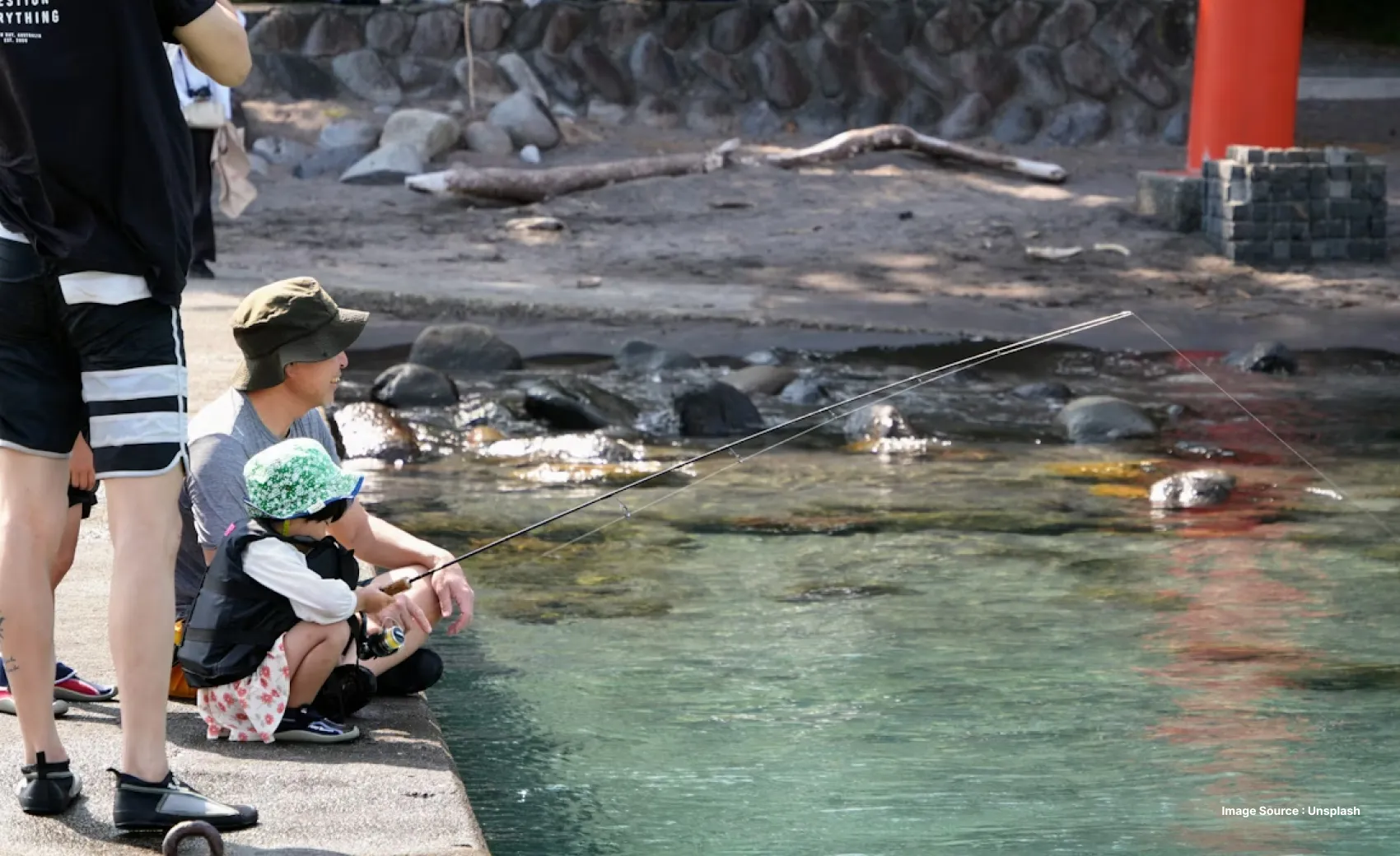 a man and a kid wearing hats and fishing by the water