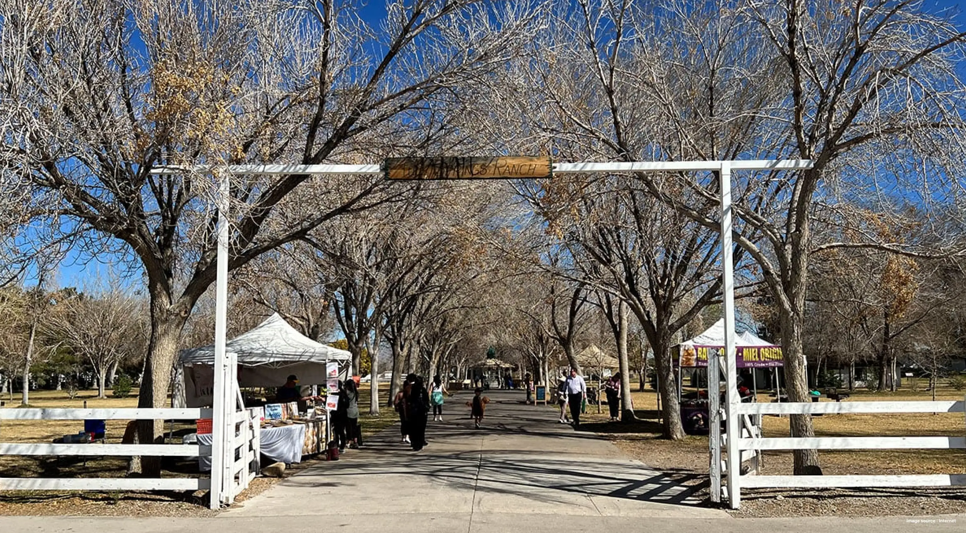 wooden banner saying "ranch" during fall season with leaf-less trees, people walk by