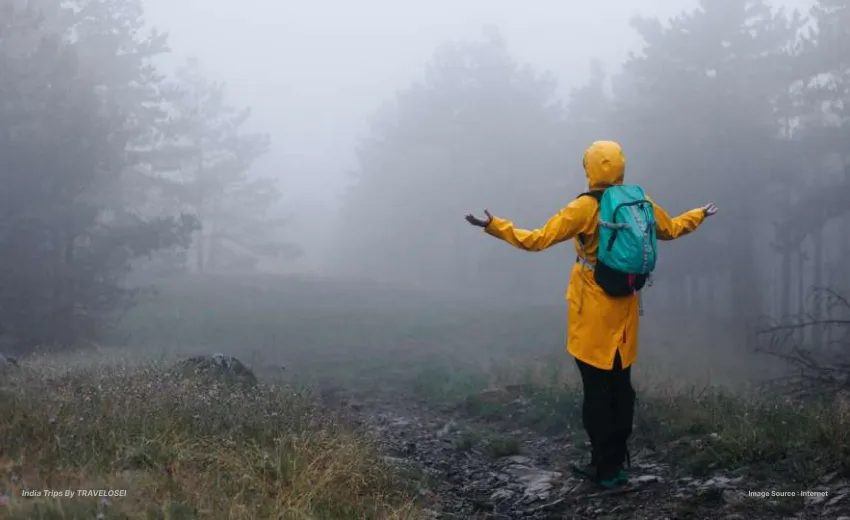 someone standing in the rain wearing a yellow jacket and carrying a blue backpack