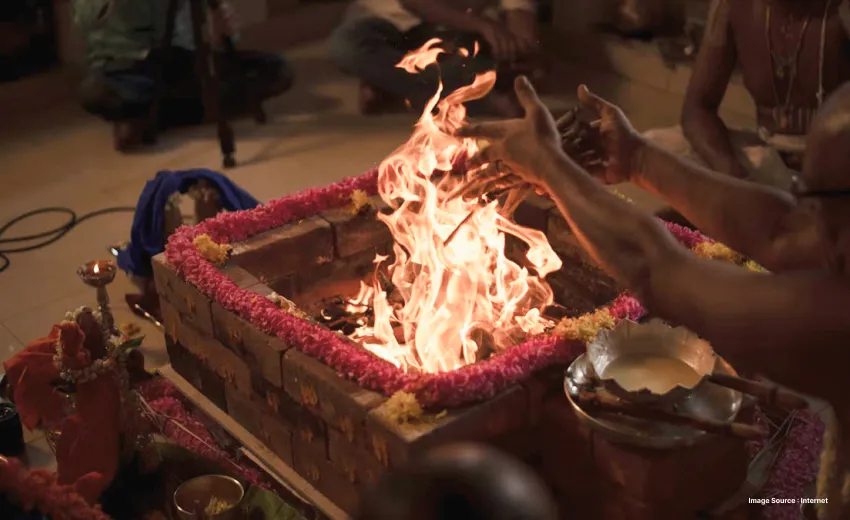 a priest performing a ritual during a hawan offering things to a sacred fire