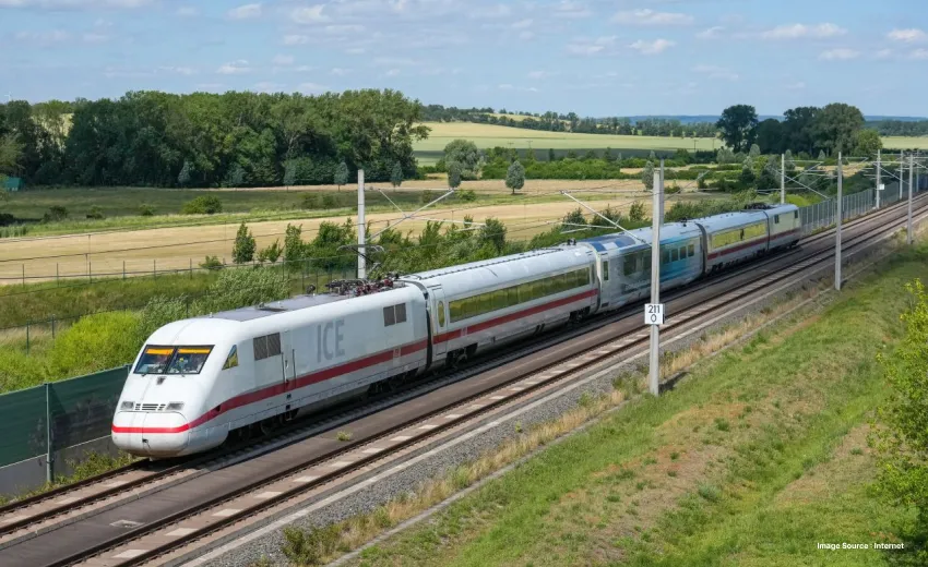 drone view shot of a european train moving on a railway track surrounded by green fields