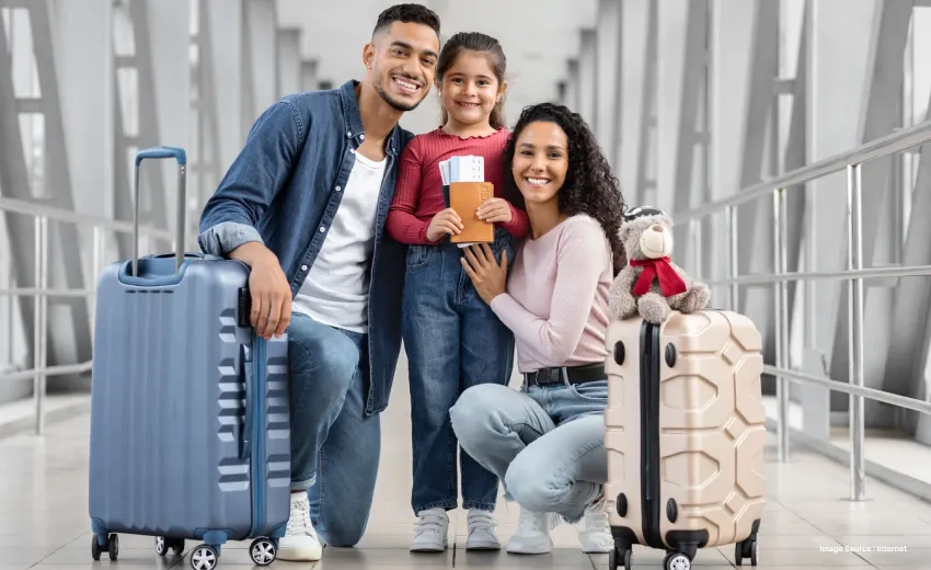 Smiling family at an airport posing with luggage and passports