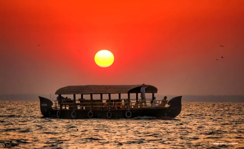Traditional houseboat cruising across tranquil waters at sunset.