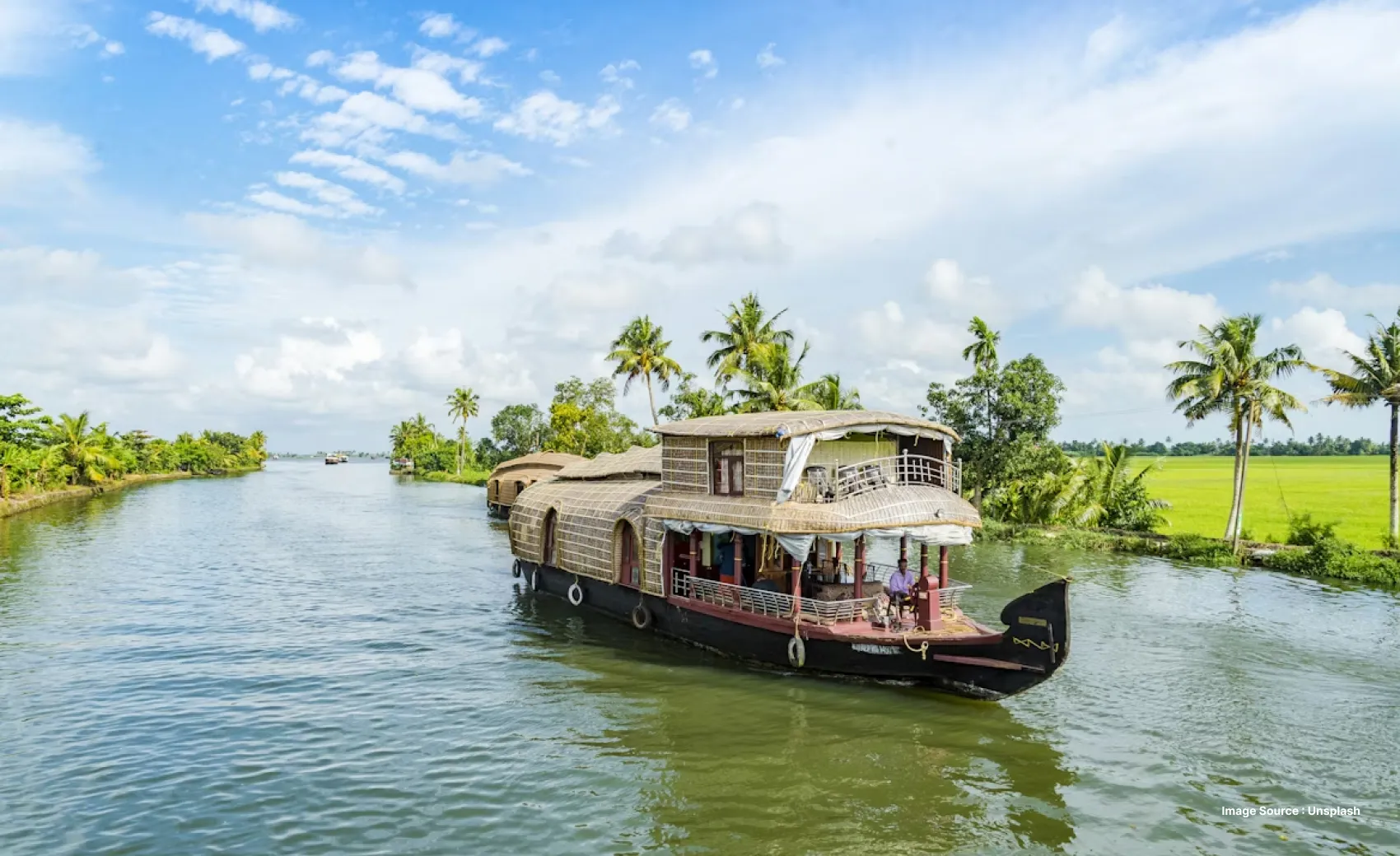 a traditional houseboat vessel cruising the backwaters fringed by palm trees
