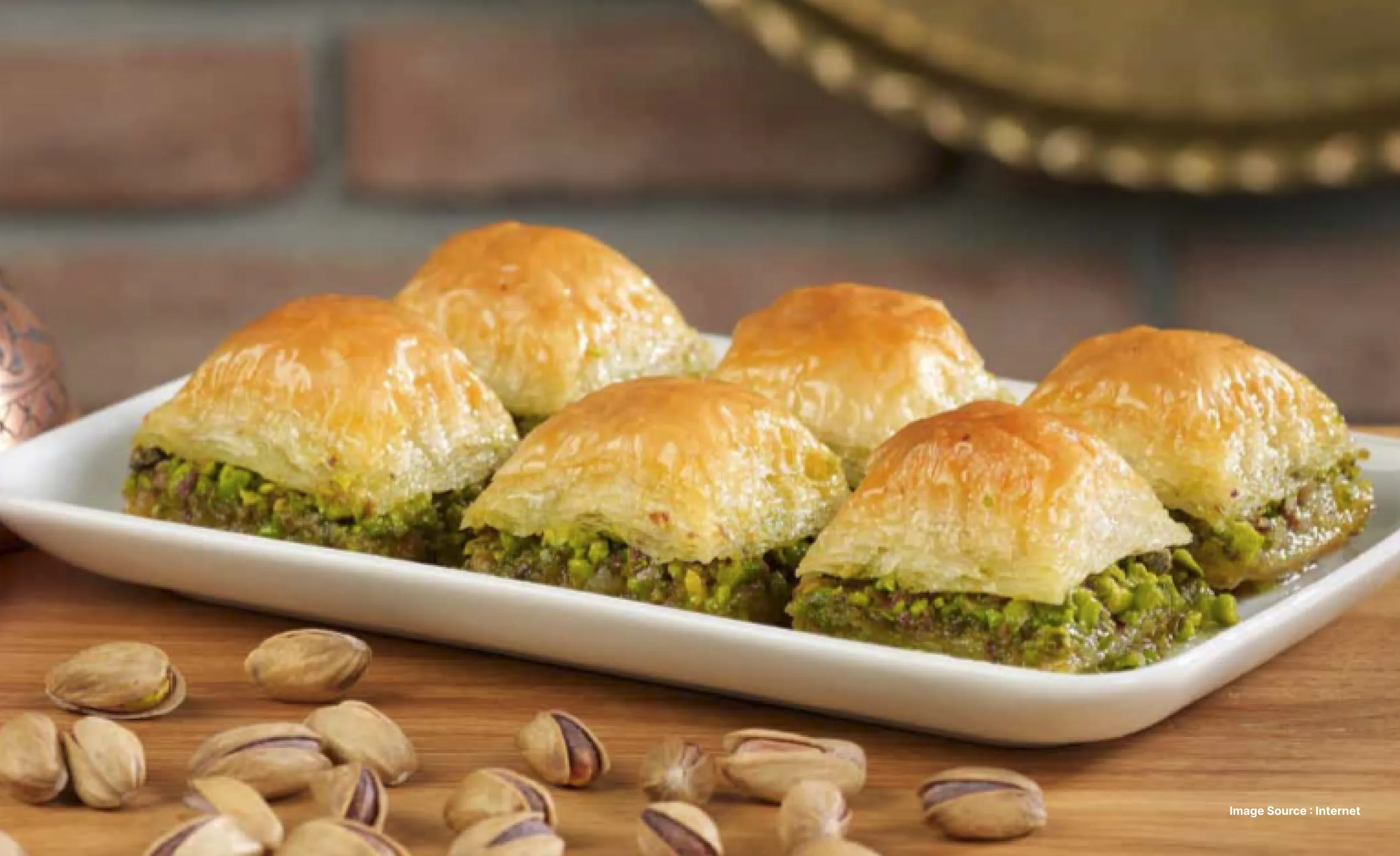 a white dish with 6 pieces of baklava with a generous filling of pistachios