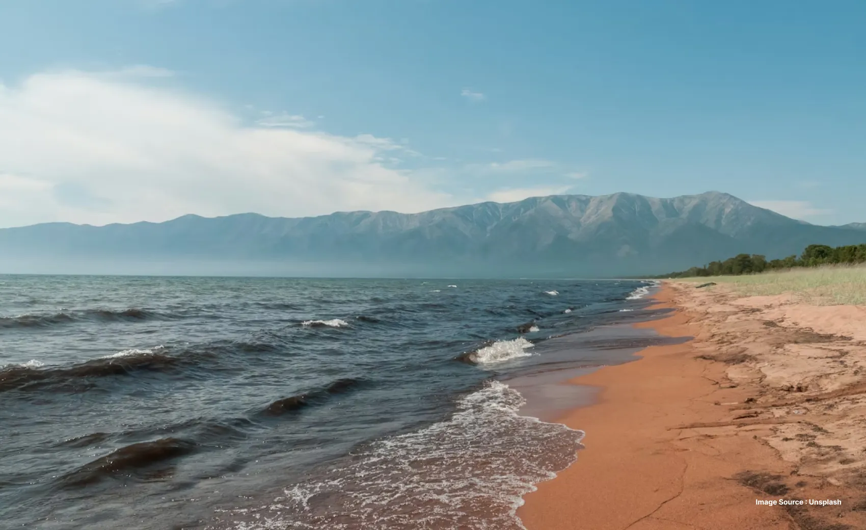 view of a beach with distant mountains and clear blue waters