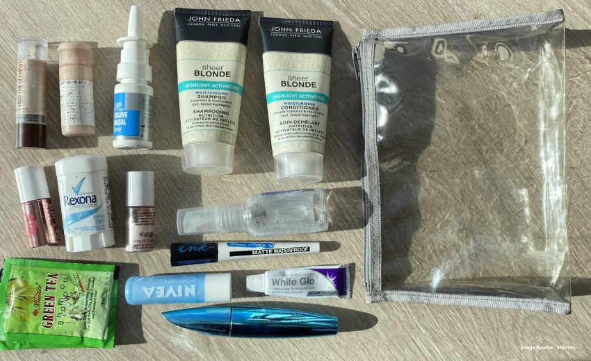 A bunch of liquid and gel items like face wash and skin care laid out on a table with a clear pouch