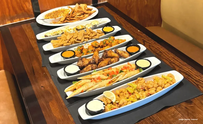 multiple appetiser platter on a wooden table with dishes like chicken nuggets at longhorn steakhouse