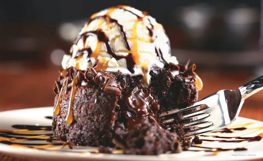 Close up of a serving of a brownie with ice cream and a result of chocolate and caramel syrup