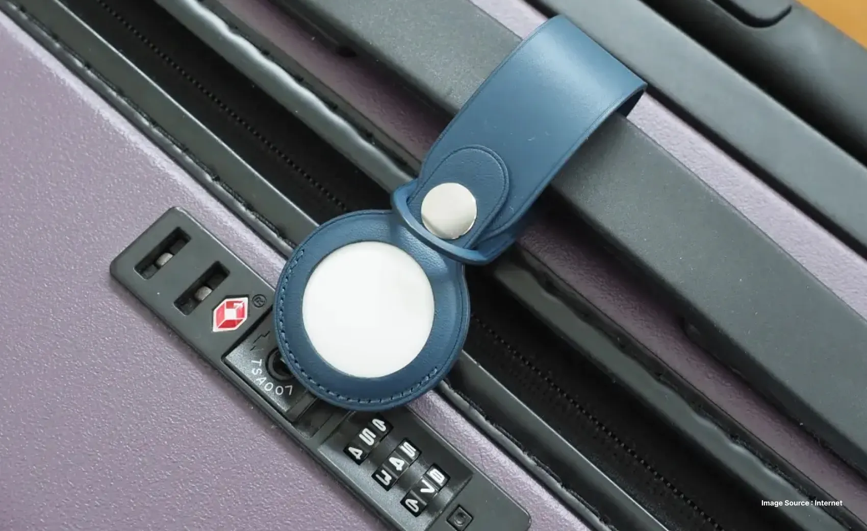 close up of a blue and white airtag cover attached to a purple suitcase