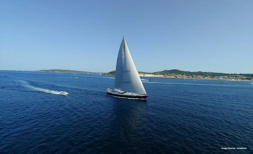 an aerial shot of a yacht sailing ahead on beautiful blue waters with distant islands
