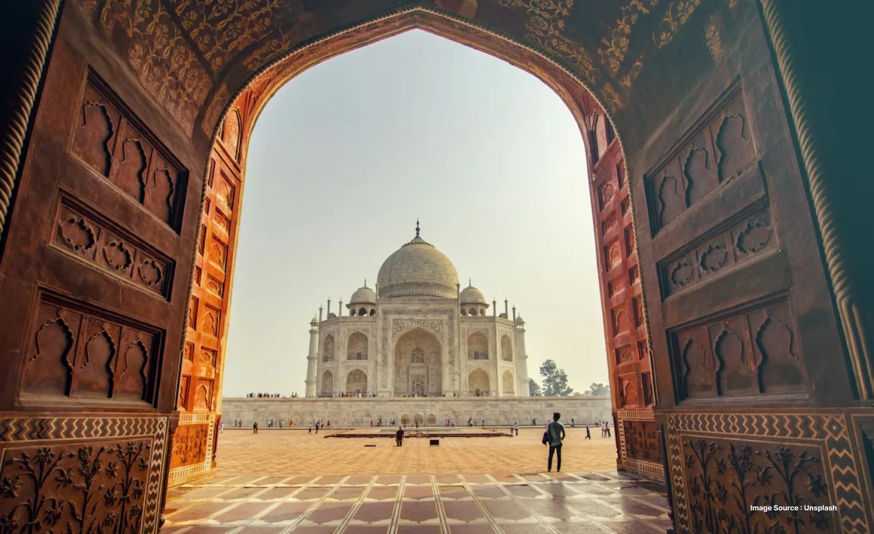 a daytime view of the taj mahal through the main entrance gate with the intricate archway