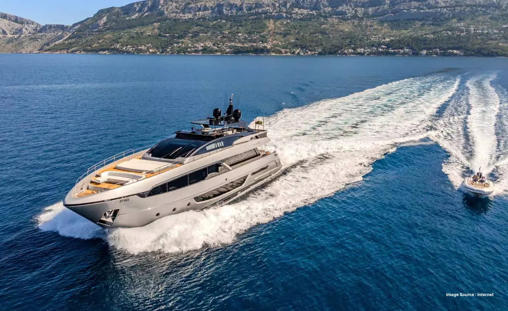 a luxurious private yacht cruising on water surrounded by green hills