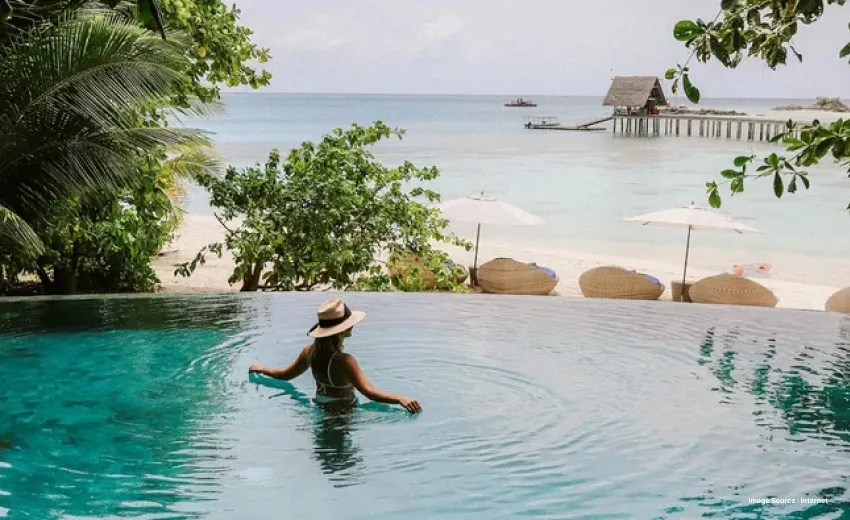 A gorgeous view of an over Water pool with a view of the beach as a woman enjoys