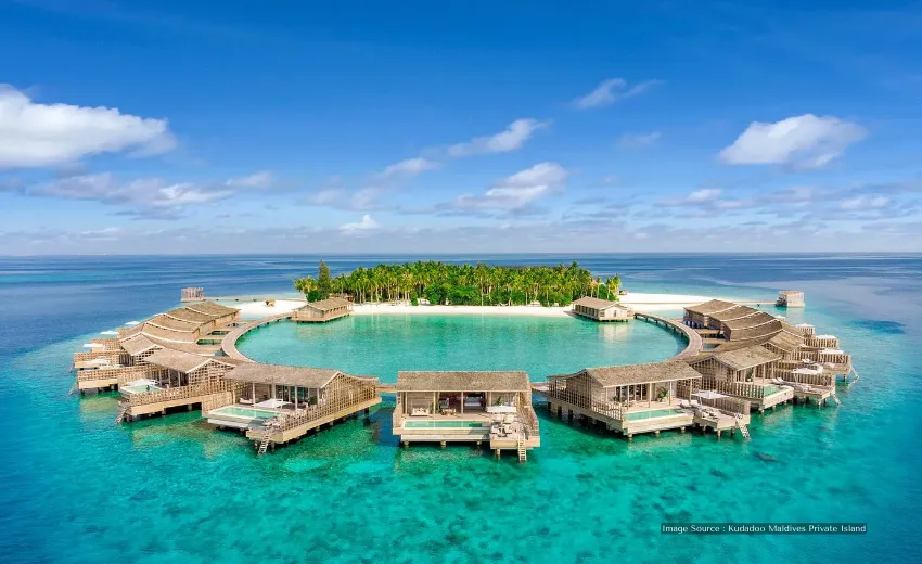Exclusive overwater villas with private pools arranged in a circle around a turquoise lagoon, luxury island resort in the Maldives.
