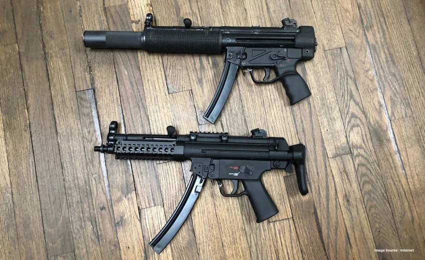 two black sniper guns laid on a wooden floor