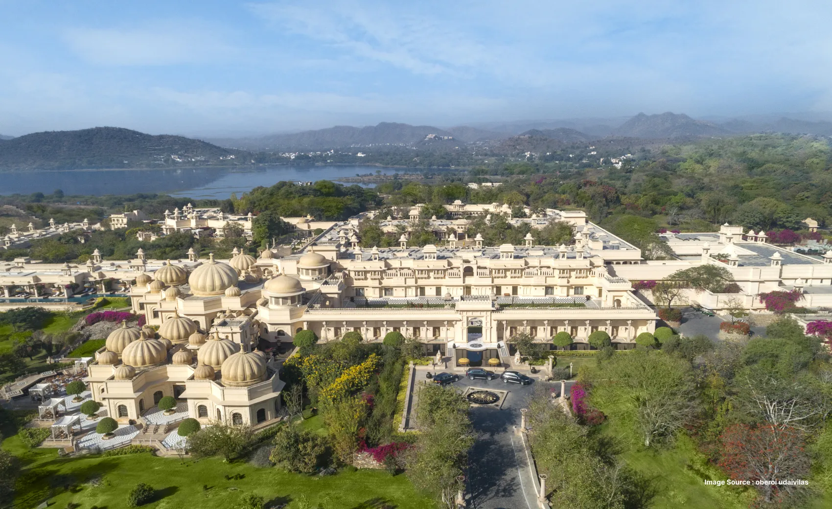 aerial shot of the expanse of oberoi udaivilas' traditional indian architecture with greenery and small hills in a distance