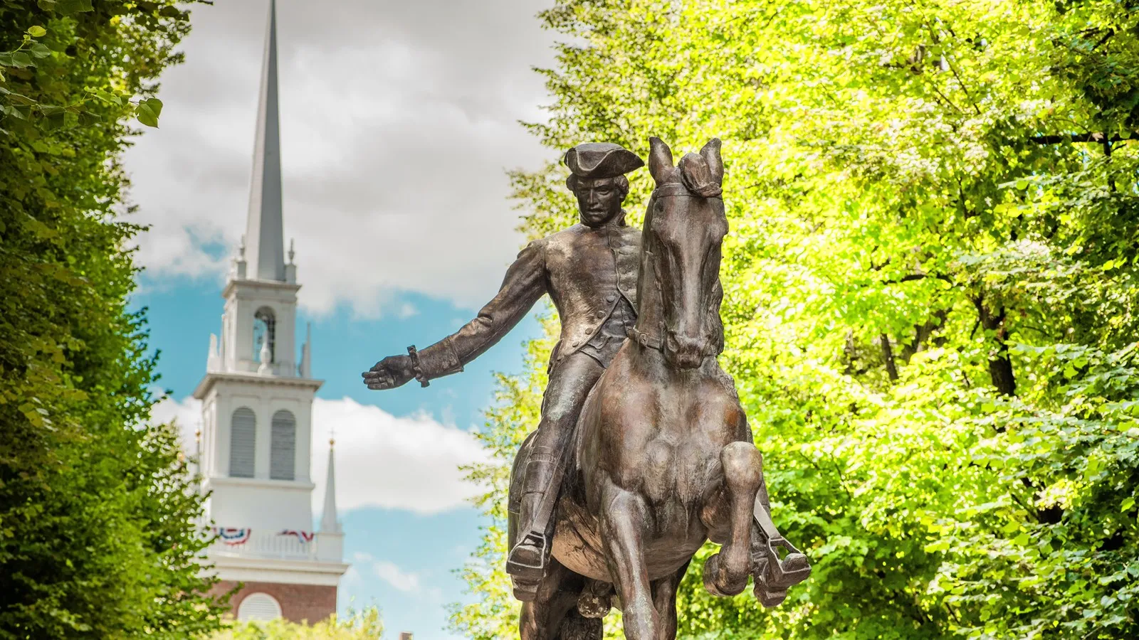 a grey statue of paul rever in front of the old north church in boston