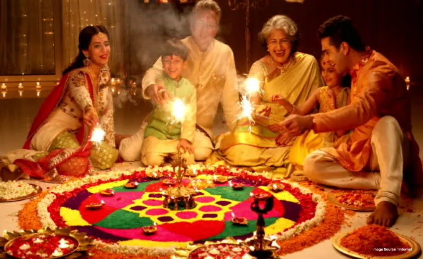 A family of 5 celebrating diwali lighting sparklers and sitting around a rangoli